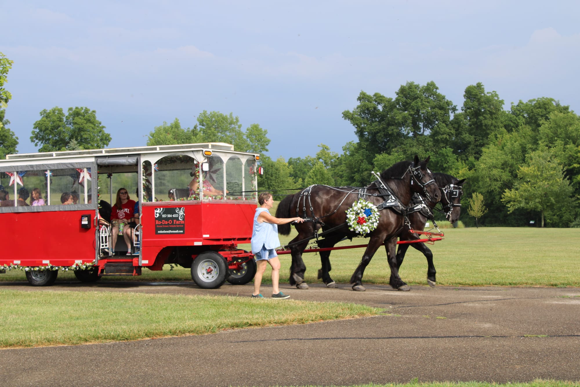 A red trolley on wheels is pulled by two dark brown horses