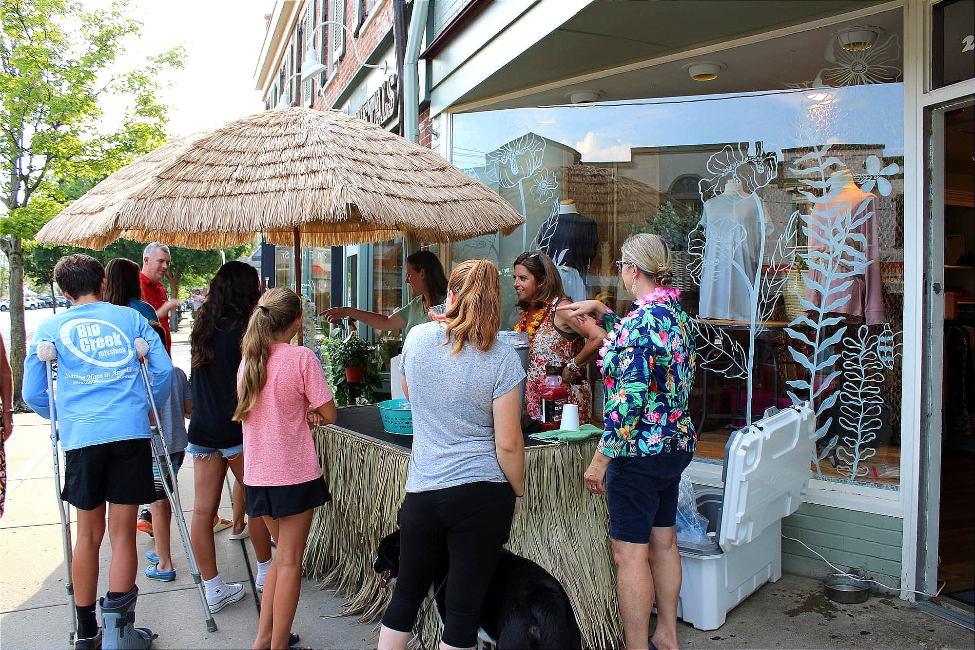 Residents stop at a booth outside Apple Tree, with vendors wearing Hawaiian shirts