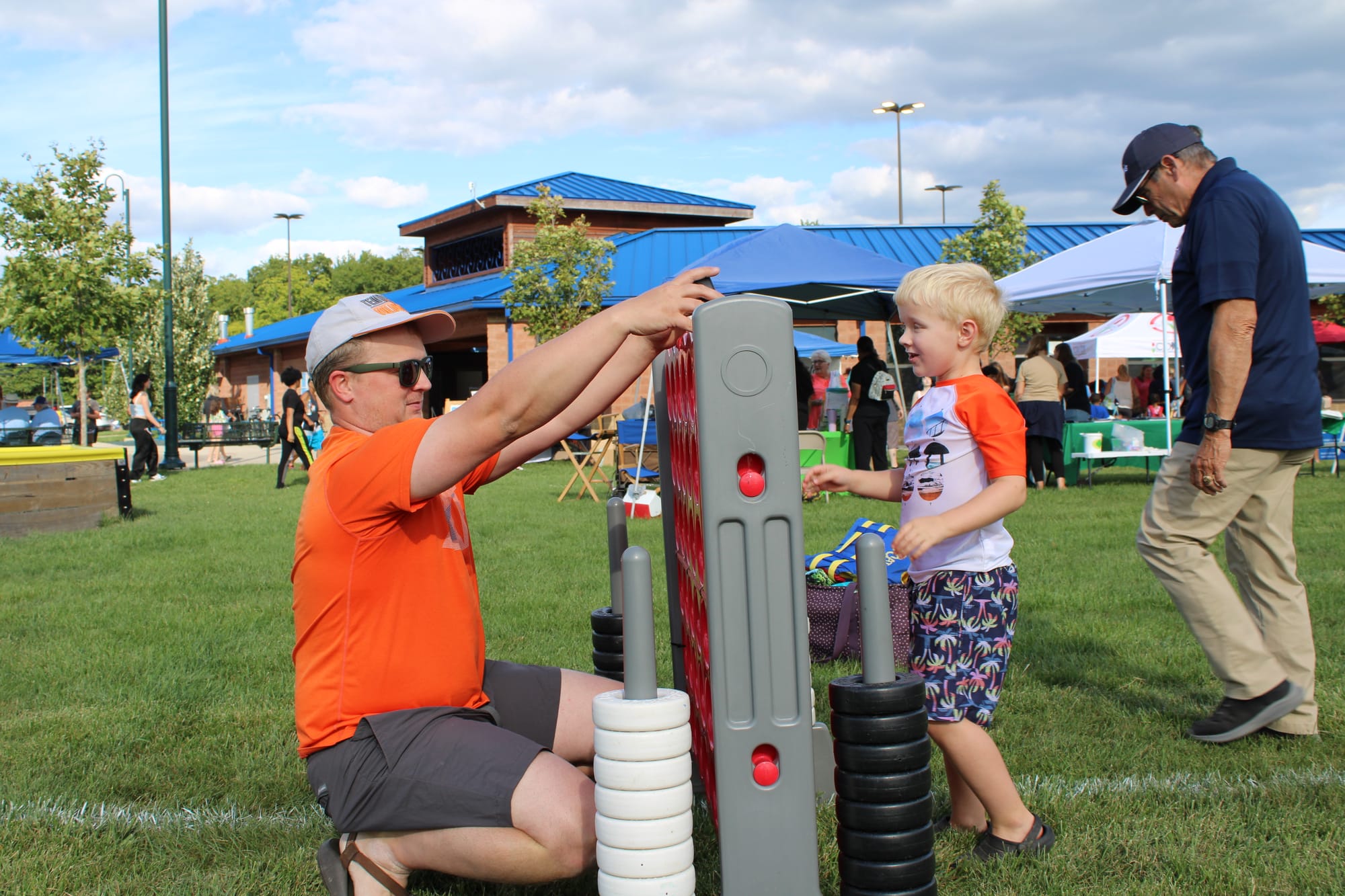 Louis Turner kneels to the left of a giant Connect Four game. Anderson Turner stands to the right