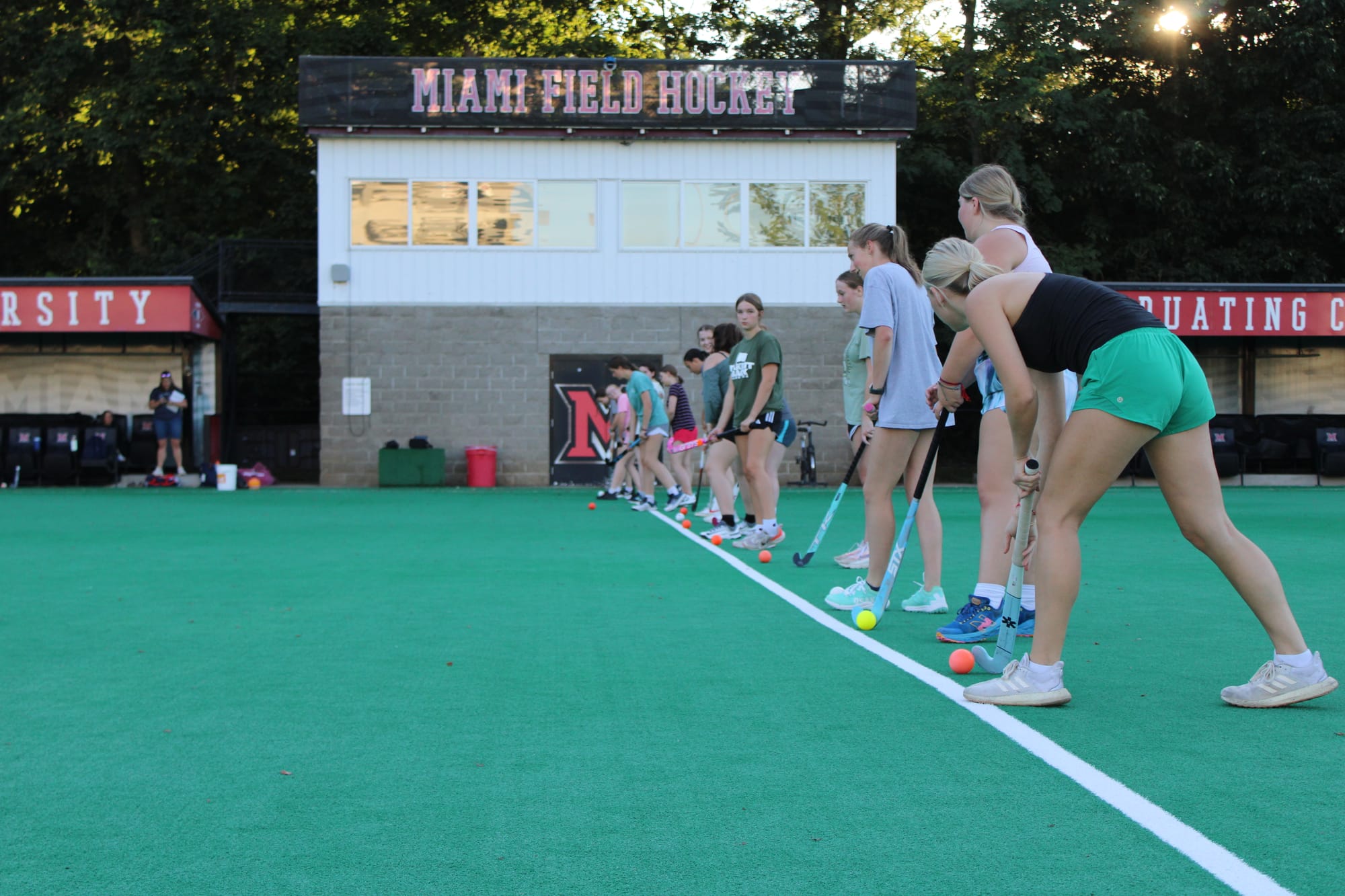 A dozen girls line up on a white line across a field