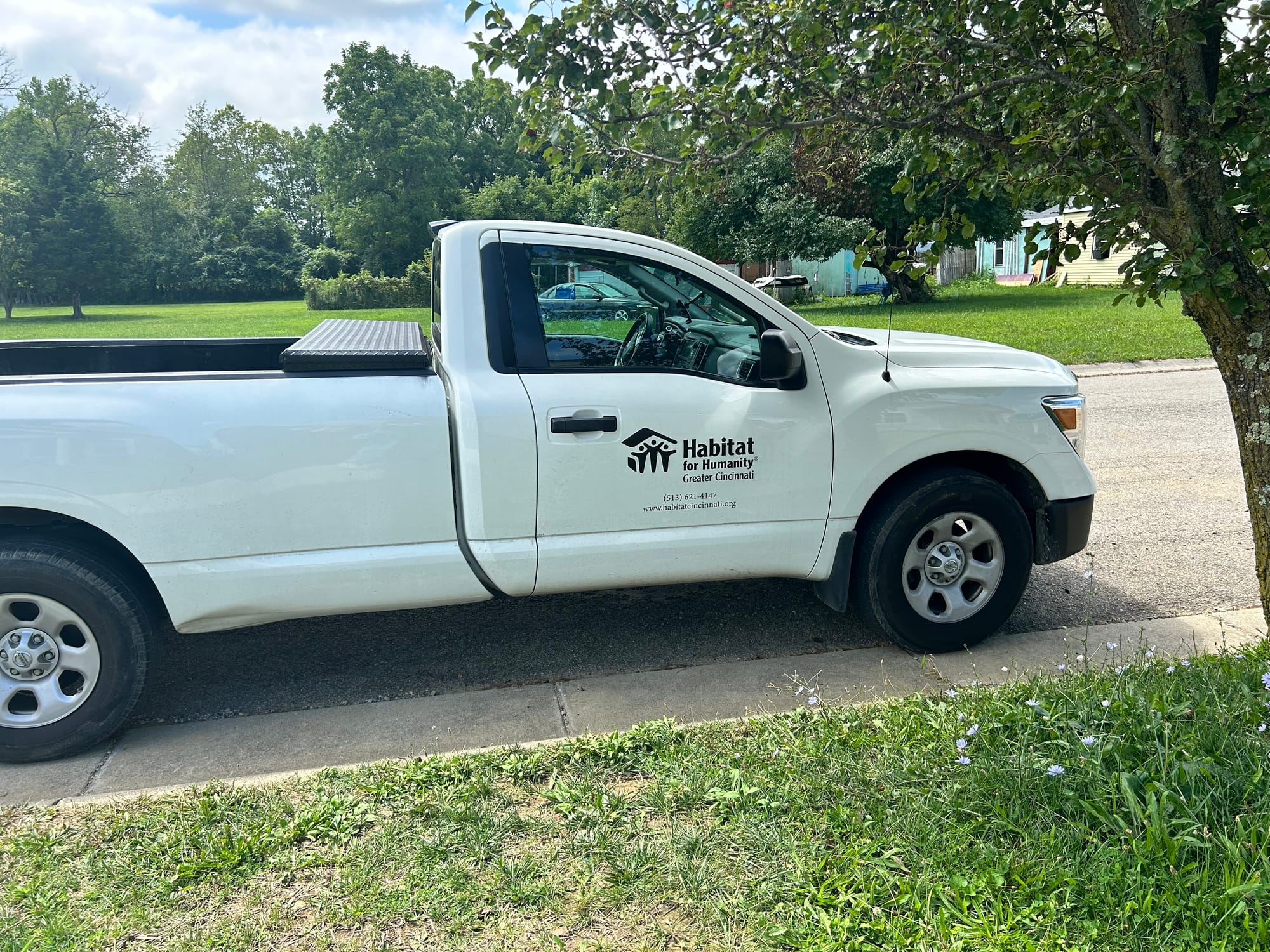 White truck sits on a street under a tree