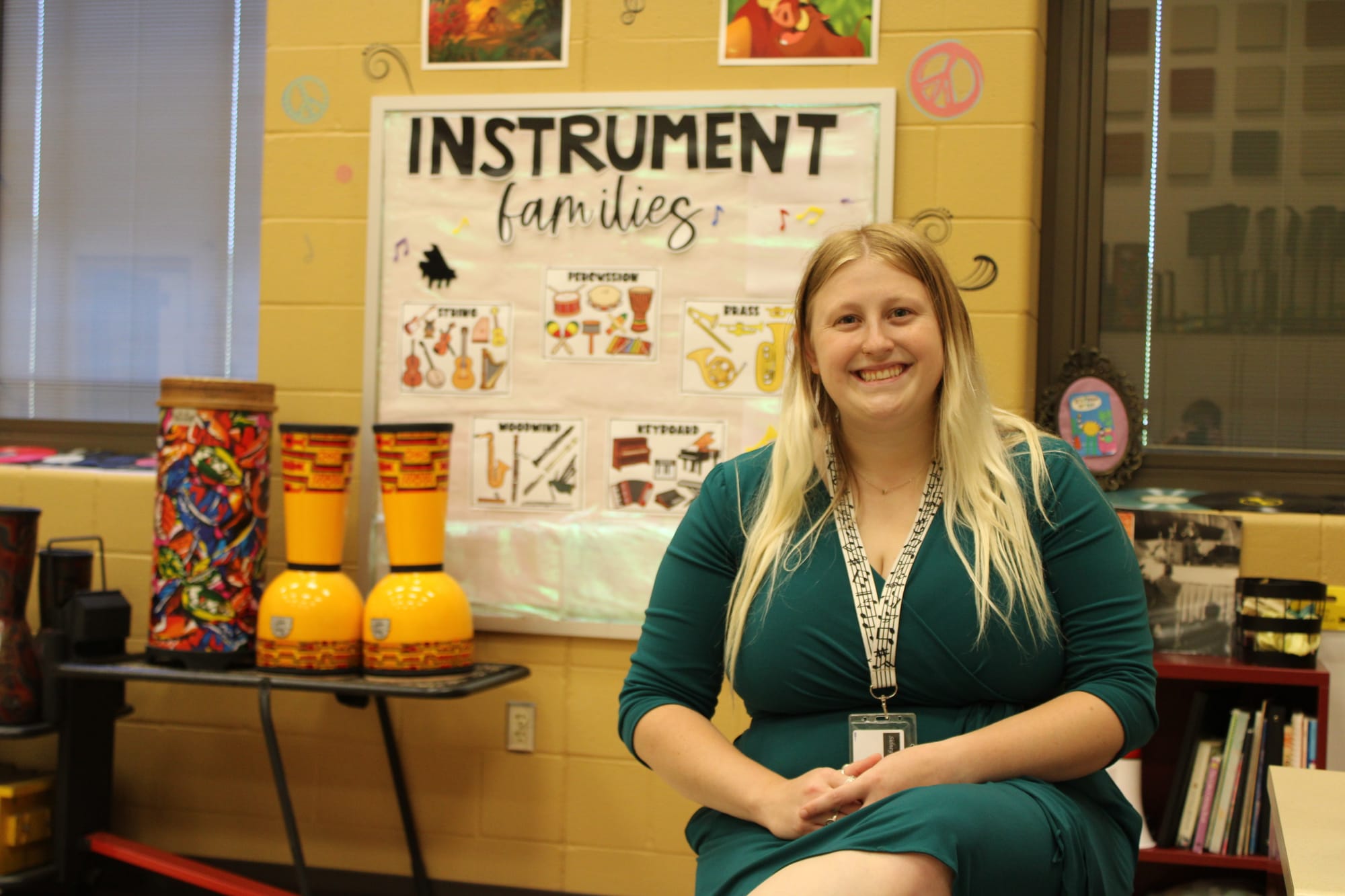 Sydney Long sits in front of a poster featuring the instrument families