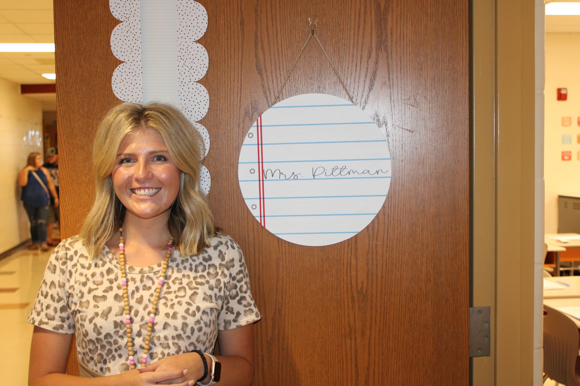 Skylar Pittman stands in front of her classroom door labeled "Mrs. Pittman"