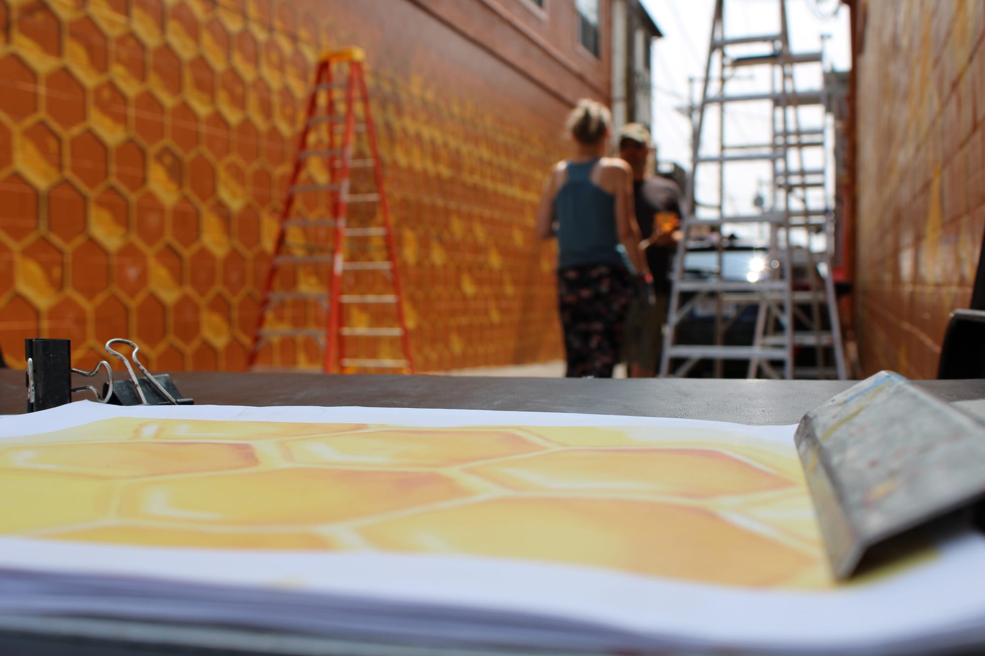 Concept art of a honeycomb sits on a clipboard in front of a mural