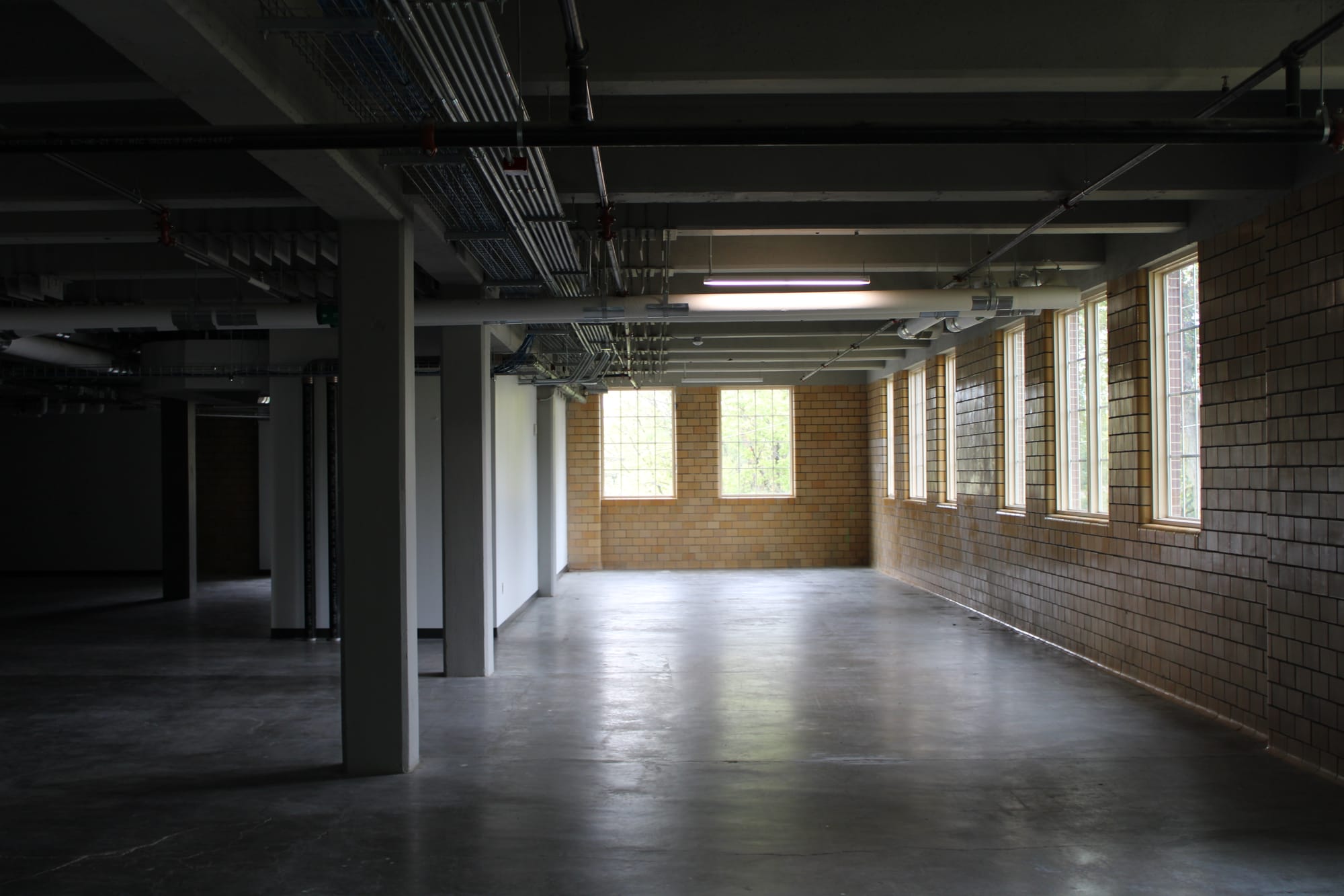 A large empty room with concrete floors and an unfinished ceiling