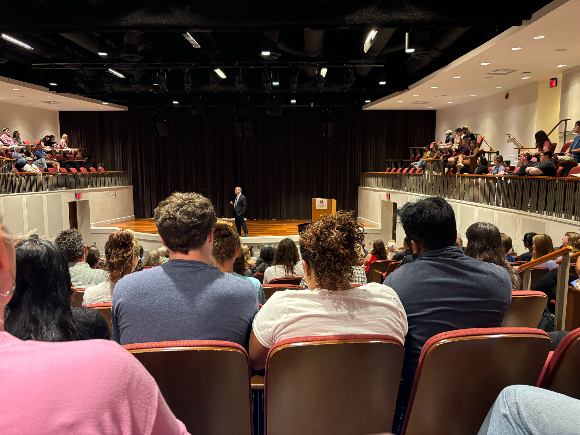 A shot of Robert Bilott from the balcony of the Harry T. Wilks Theater with people in the seats