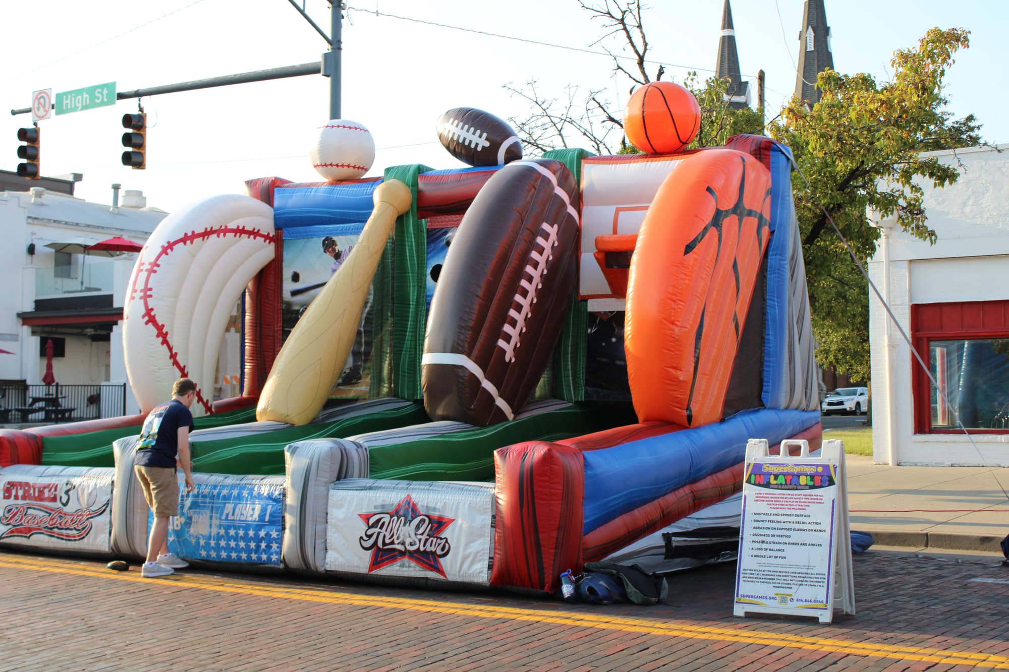 Inflatable sports game decorated with a football, basketball and baseball on a brick street