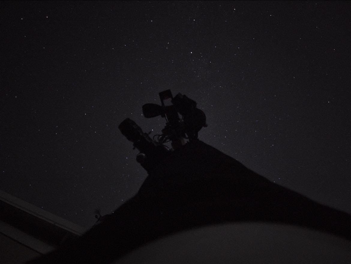 The silhouette of astrophotography equipment in front of a star-filled night sky