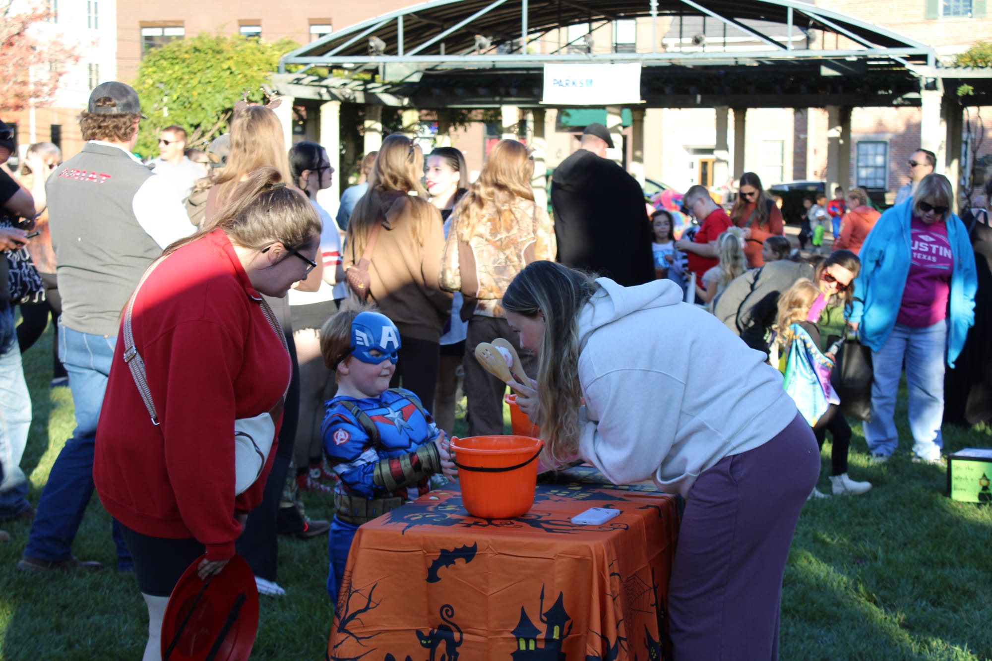 A child dressed as Captain America getting candy at a game booth