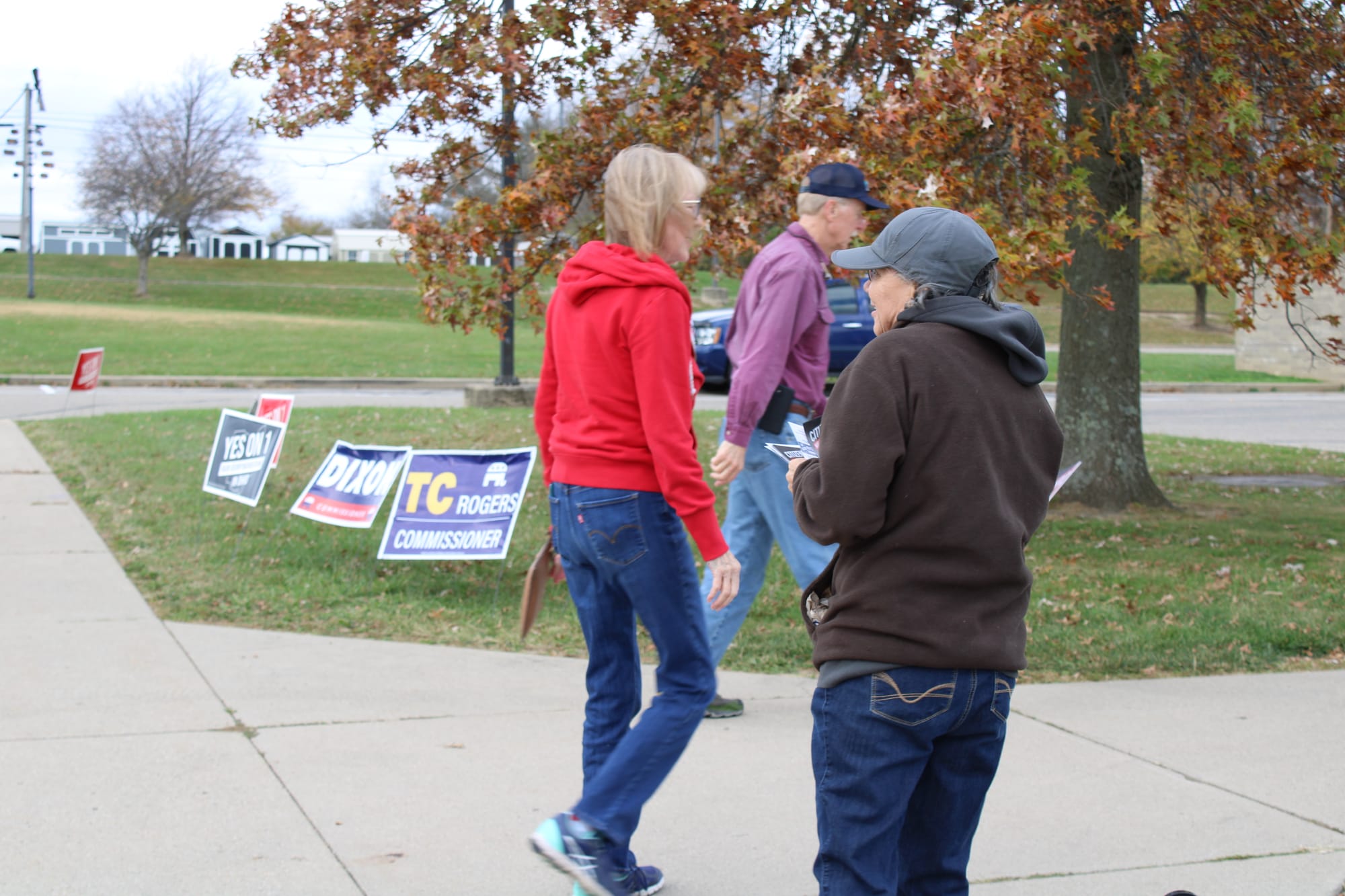 Ellen Price hands out flyers as two voters walk past