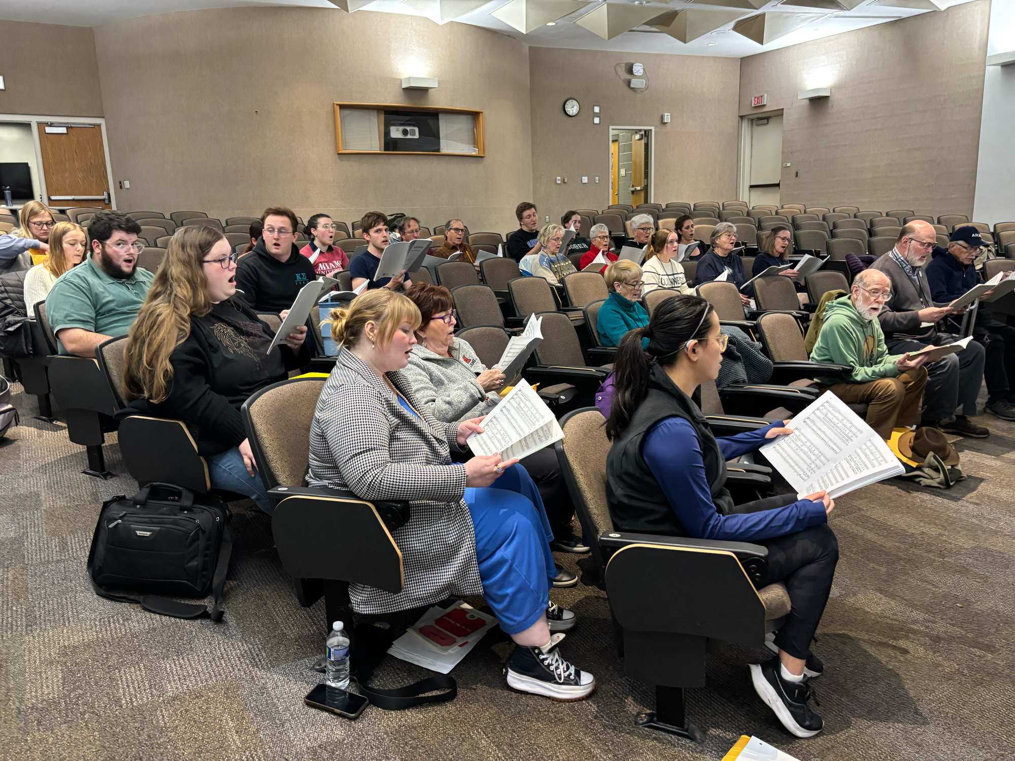 The choir sitting down and rehearsing the piece "Gloria."