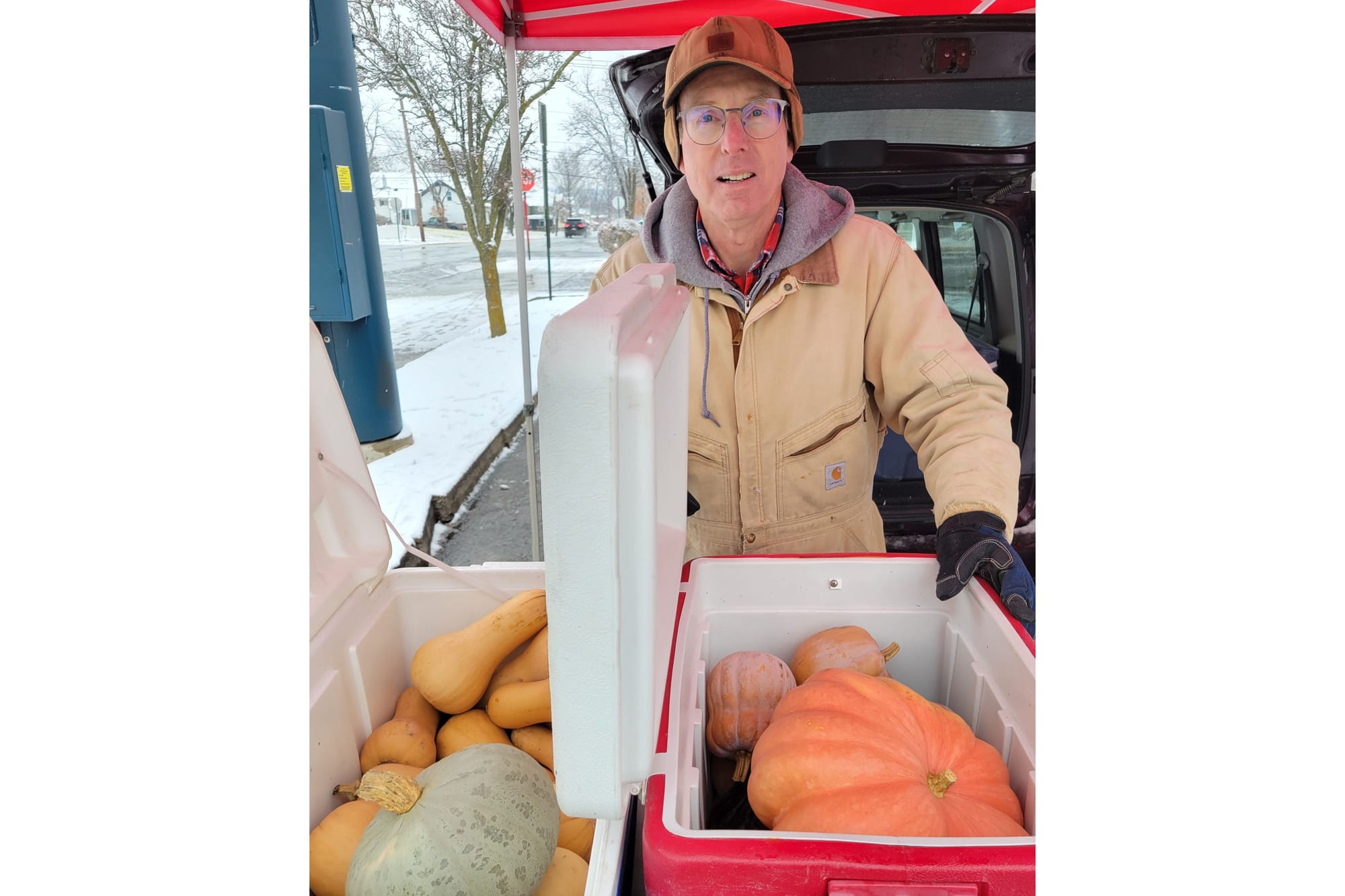 Craig Harkrider stands behind two coolers full of squash