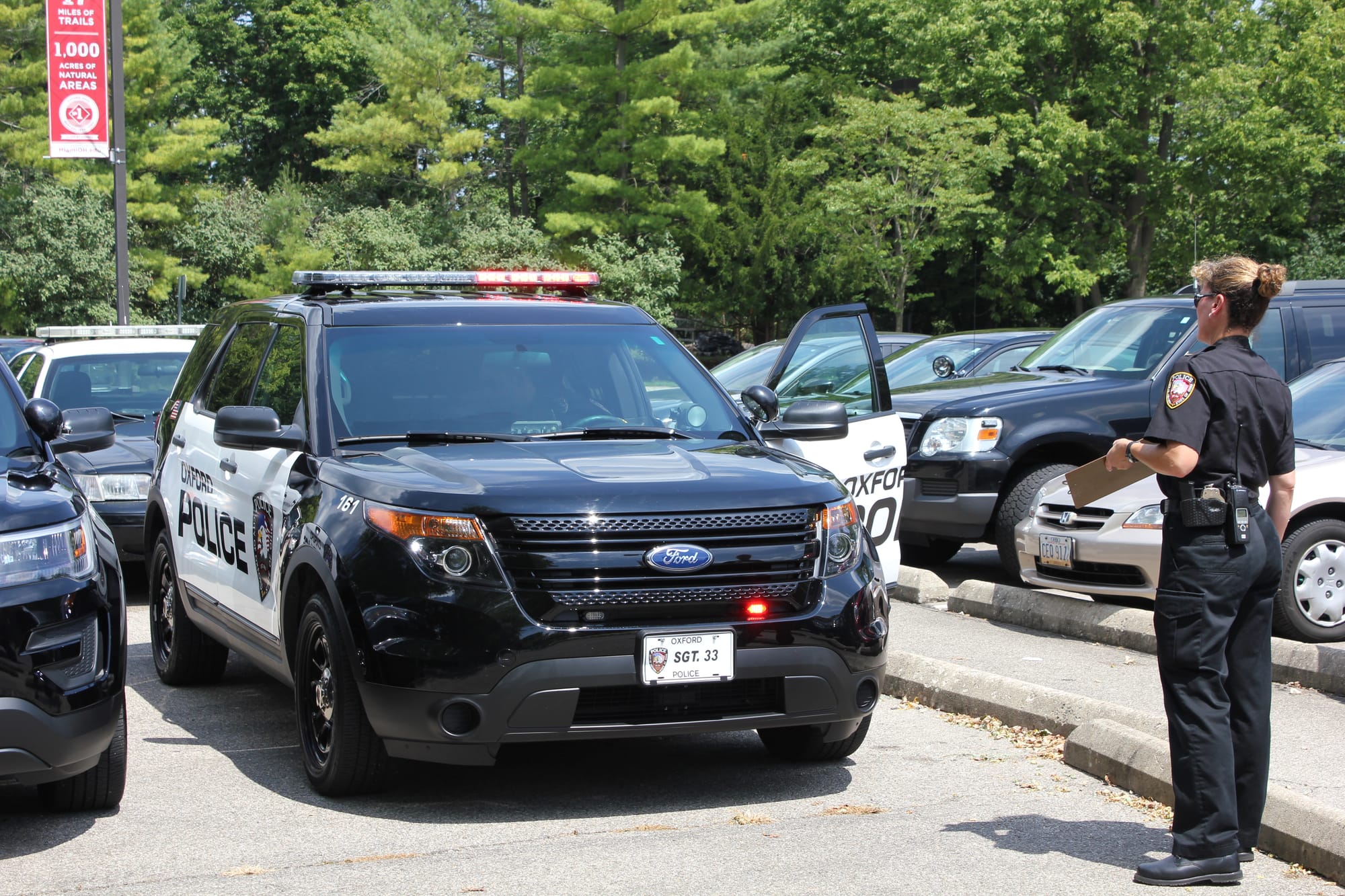 Lara Fening stands next to an OPD cruiser in a full parking lot