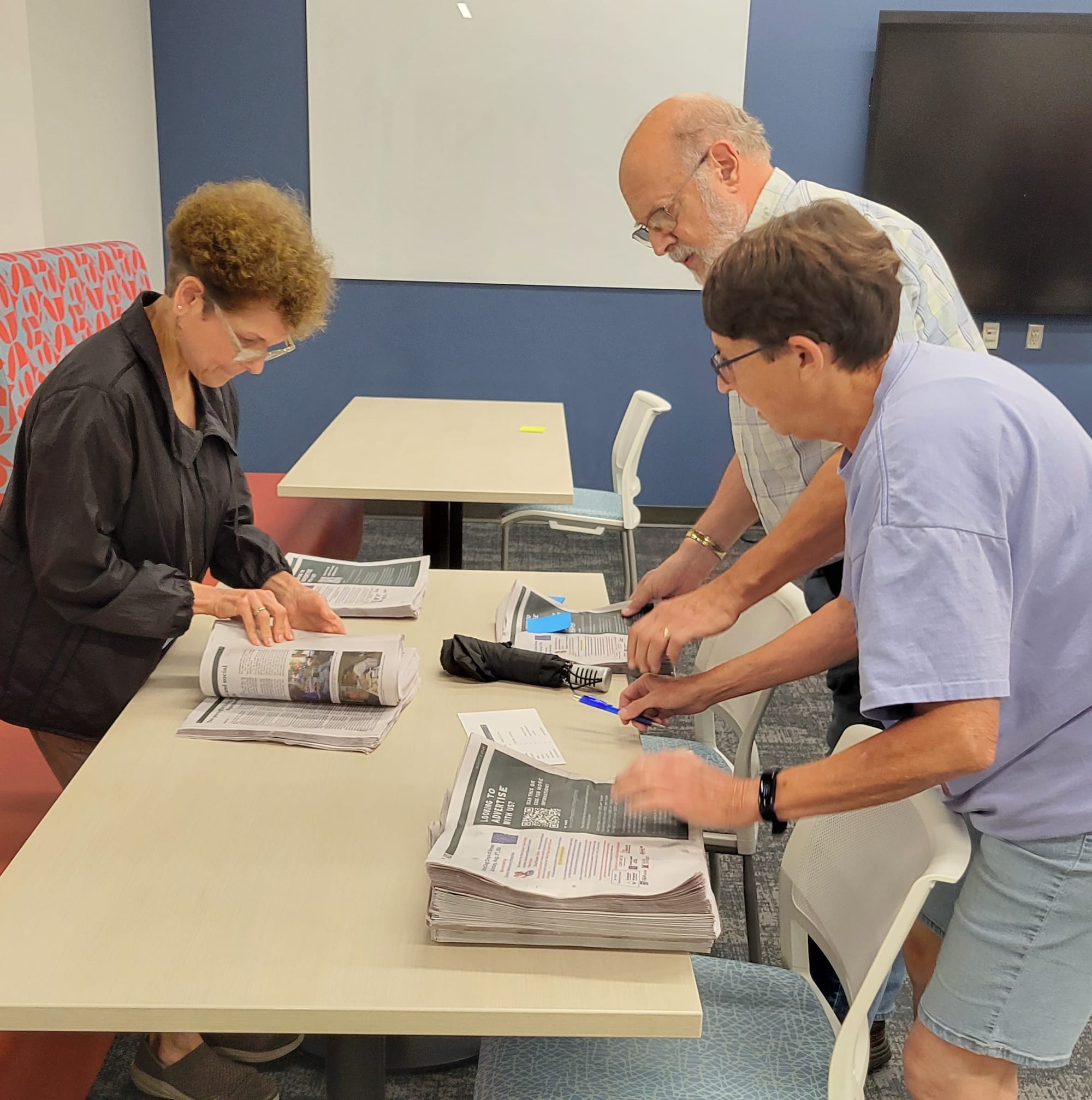 Volunteers count out several stacks of newspapers