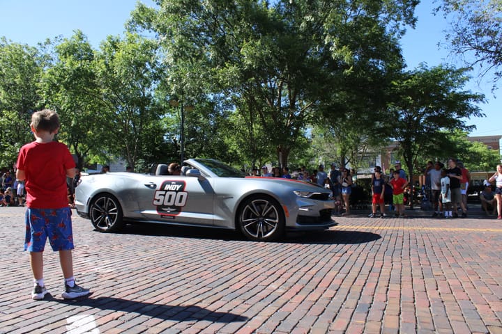 A little kid in red stares at Indy 500 pace car during the Freedom Festival Parade. Photo by Taylor Stumbaugh