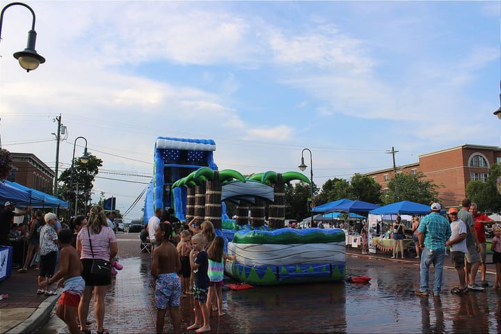 A tropical-themed inflatable waterslide sits on Main Street in Oxford. Several kids wait in line