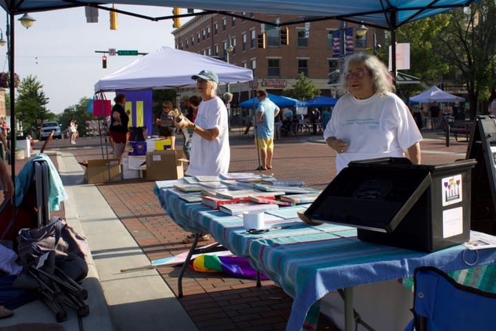 Two women stand behind a table with several books laid out on it