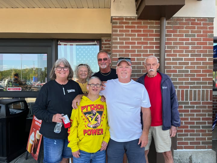 Tommy Irrgang, wearing a bright yellow "Python Power" shirt, smiles with his family outside Kroger