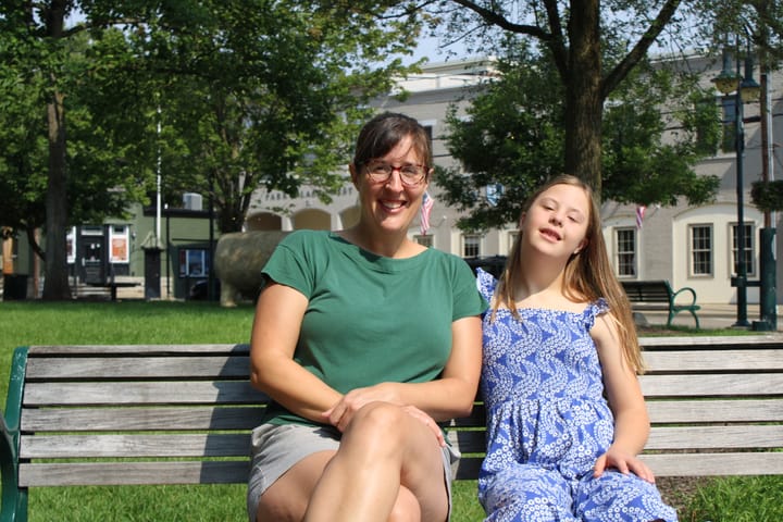 Pepper Stetler sits next to her daughter Louisa Stetler on a bench in a park