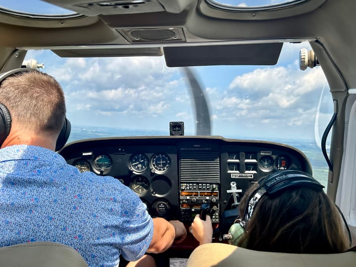 A man in blue and a young brunette girl sit in the front of the plane.