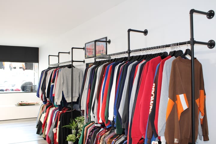 Several full clothing racks of different colored sweaters and crewnecks