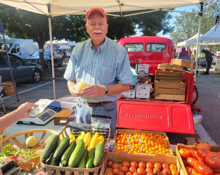 Jim Gierenger stands behind a booth with colorful tomato varieties