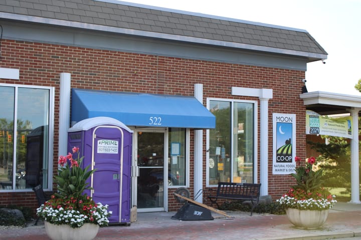 Front view of 522 S. Locust St., a brick building, with a sign for MOON Co-op on the right