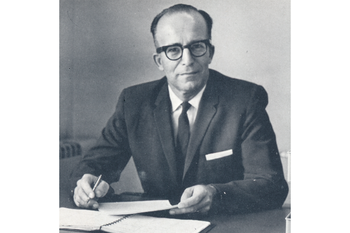 Black and white photo of Robert W. Bogan sitting behind a desk with a notebook