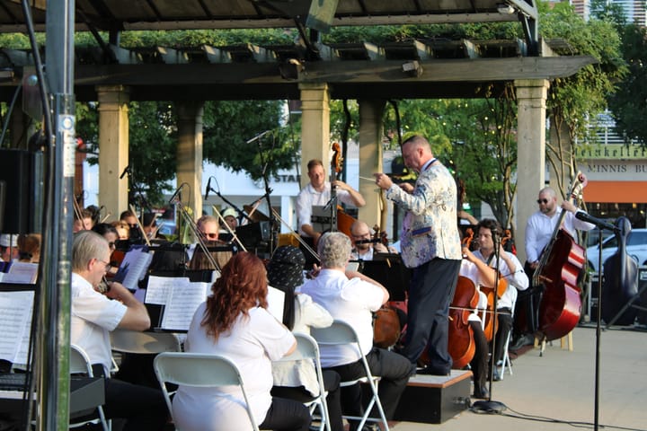 An orchestra performs at an outdoor venue