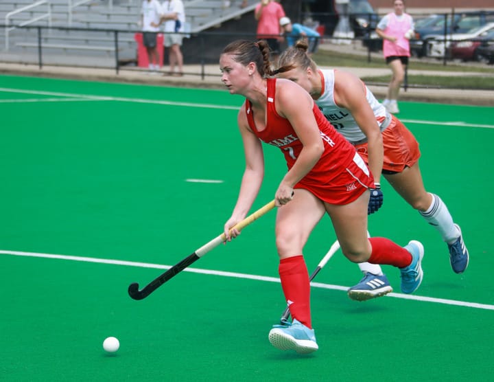 Carlie Servis chases after a ball on a bright green field