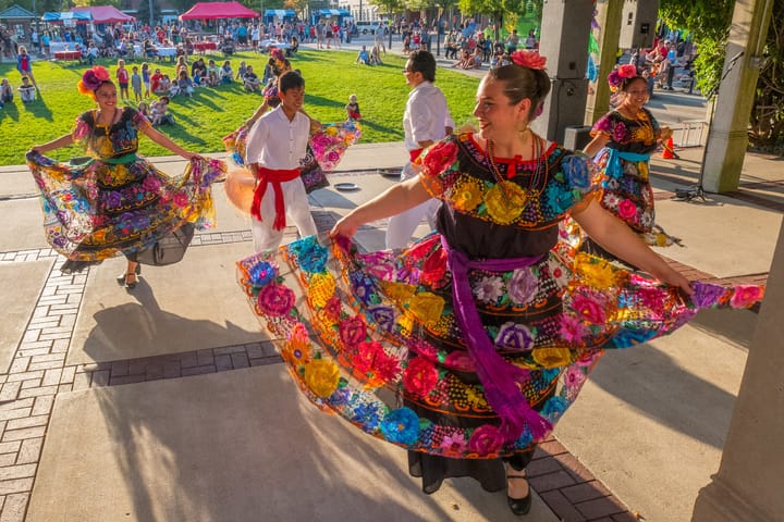 Women dance in brightly colored and patterned dresses