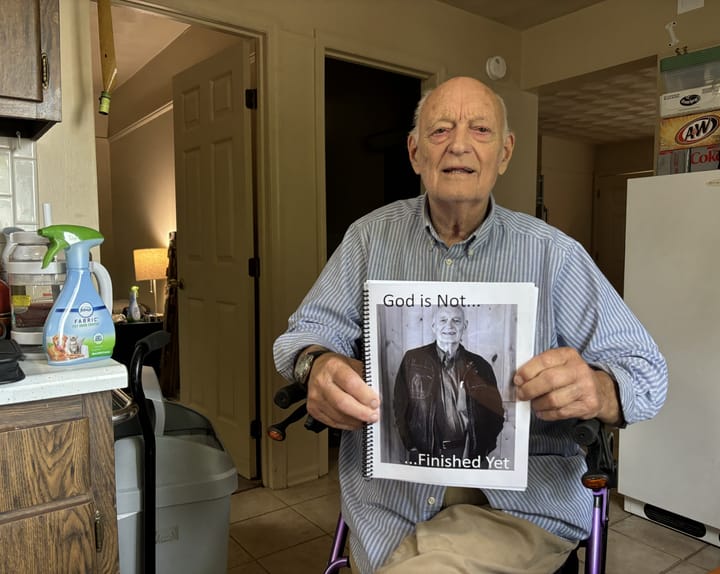 Charles Roberts seen in his kitchen holding a copy of his upcoming book