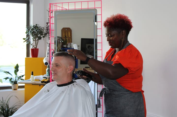 Kiki Harmon cuts Brett Smith's hair while smiling in her shop