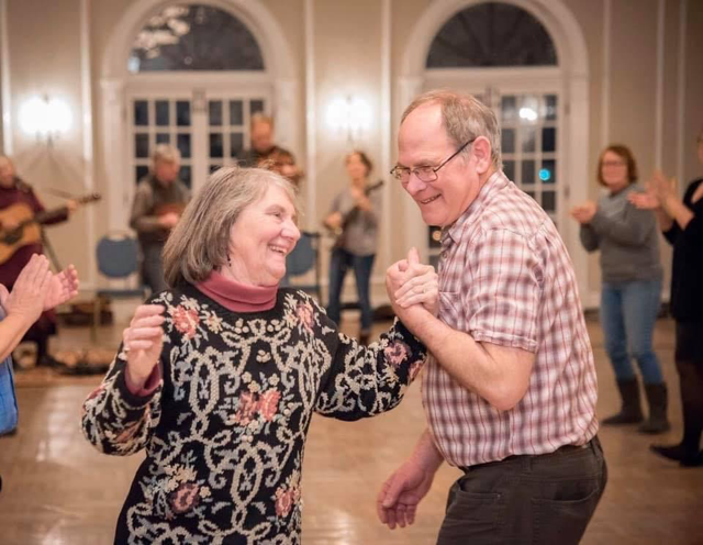 Two people smile and dance in front of a band in the Oxford Community Arts Center ballroom