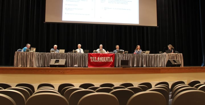 The Talawanda Board of Education sits behind a table on stage in an auditorium