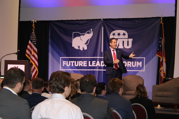 Bernie Moreno stands on a stage in front of a banner which reads "Future Leaders Forum"