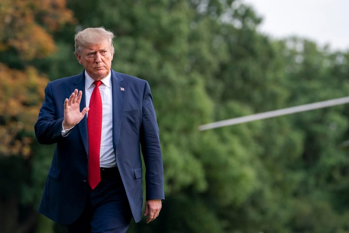 Donald Trump walking in front of trees