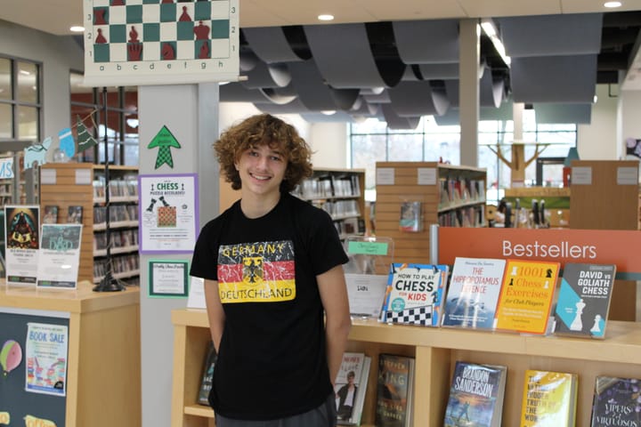 Isaac Coffin stands in front of a chess problem board in the Oxford Lane Library