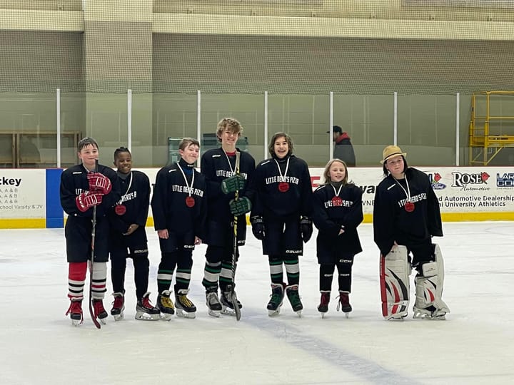 Seven young hockey players pose on the ice for a photo