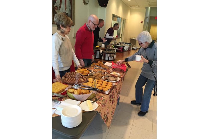 People dish up plates of baked goods and chili