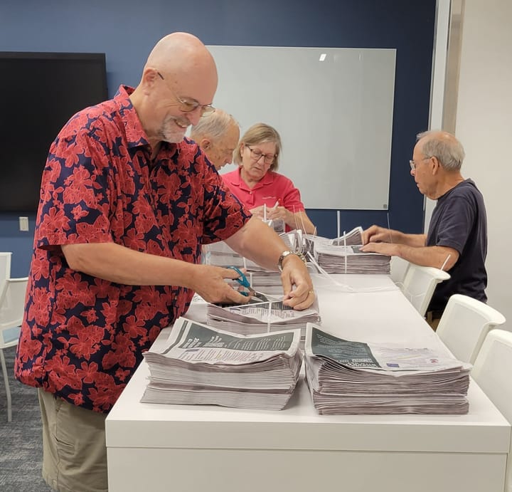 Volunteers count out several stacks of newspapers