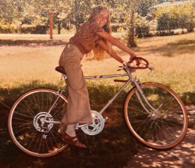 A girl poses on a bicycle in a grainy photo