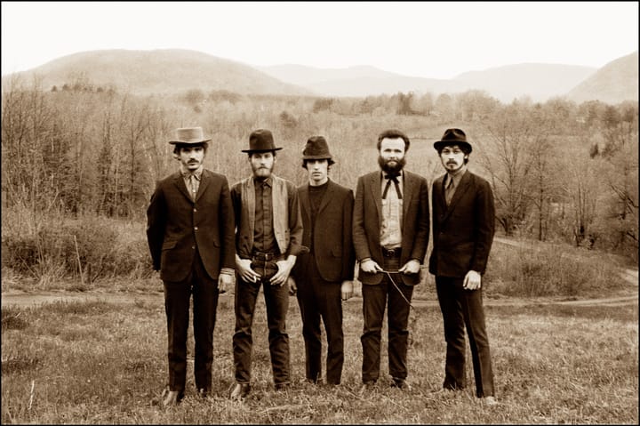 Sepia photo of five members of The Band standing in a field