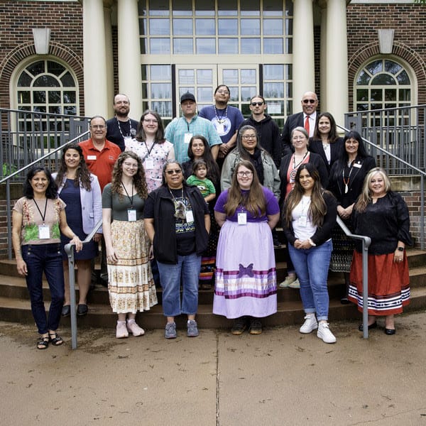 A couple dozen people pose for a photo on a stairway