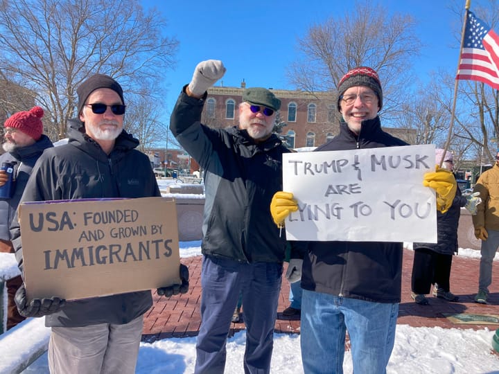 Protestors hold signs saying "Trump and Musk are lying to you"