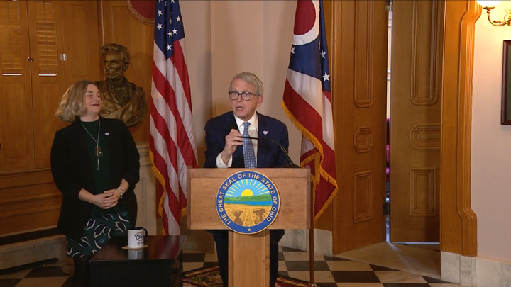 Mike DeWine stands behind a lectern, Kimberly Murnieks on his left