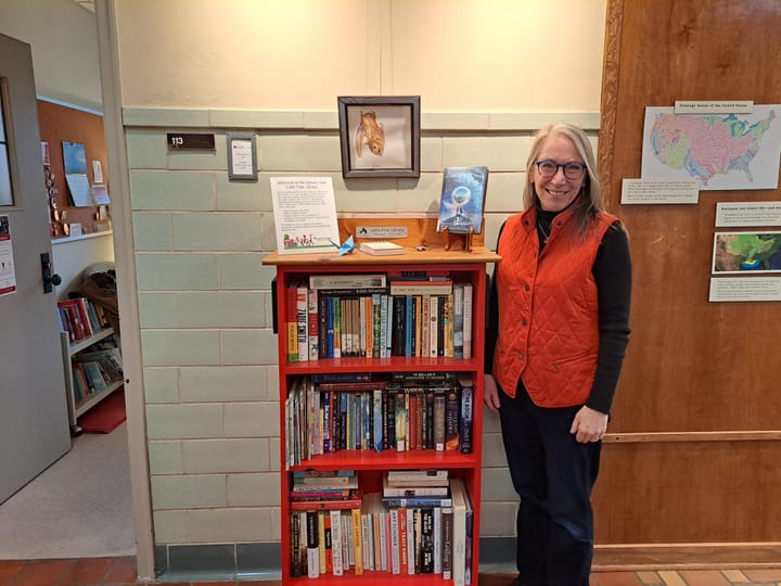 Connie Malone stands next to a red bookshelf in a hallway